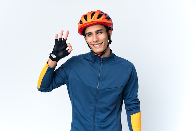 Homem jovem ciclista isolado na parede mostrando sinal de ok com os dedos