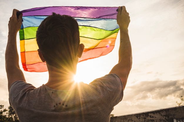 Homem jovem, com, bandeira grande, em, LGBT, cores, e, céu, com, sol