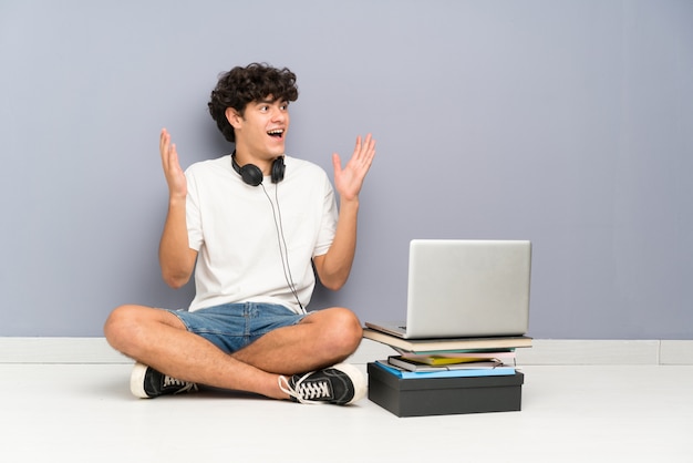 Homem jovem, com, seu, laptop, sentando, um, a, chão, com, surpresa, expressão facial