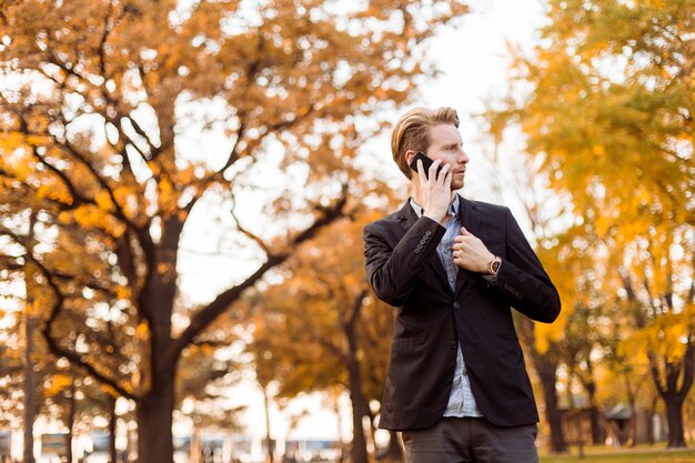 Homem jovem, com, telefone móvel, em, a, outono, parque