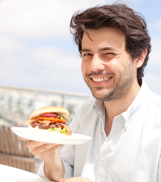 Homem jovem, comer, um, hamburguer