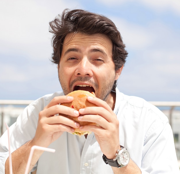 Homem jovem, comer, um, hamburguer