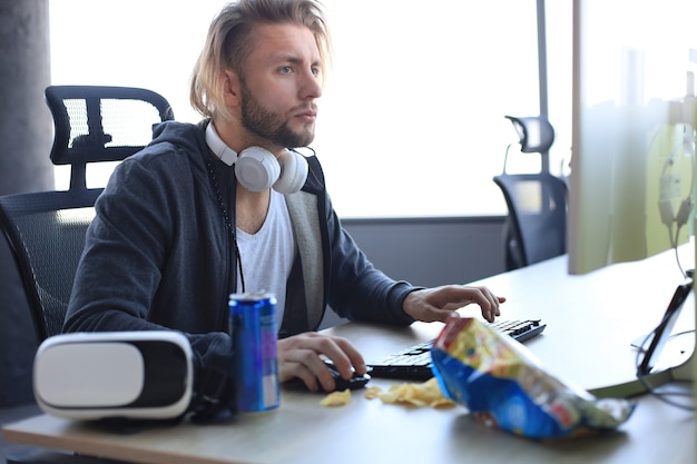 Homem jovem concentrado em roupas casuais usando computador, streaming de vídeo ou vídeo passo a passo.
