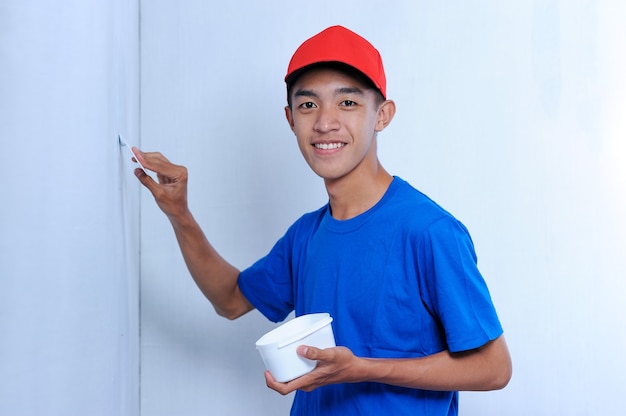 Homem jovem construtor asiático aplicando massa de gesso na parede branca. Reboco de parede para parede de acabamento.