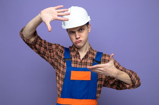 Homem jovem construtor vestindo uniforme mostrando gesto de foto desagradável