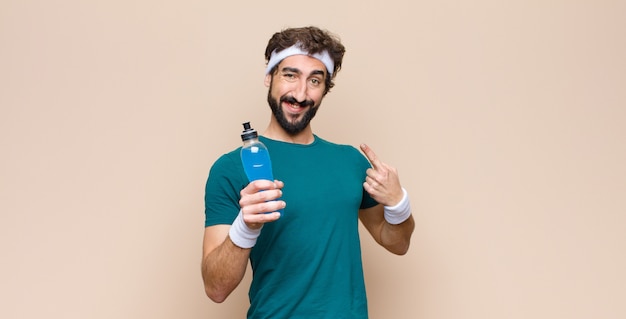 Foto homem jovem de esportes com uma garrafa de bebida energética contra parede plana