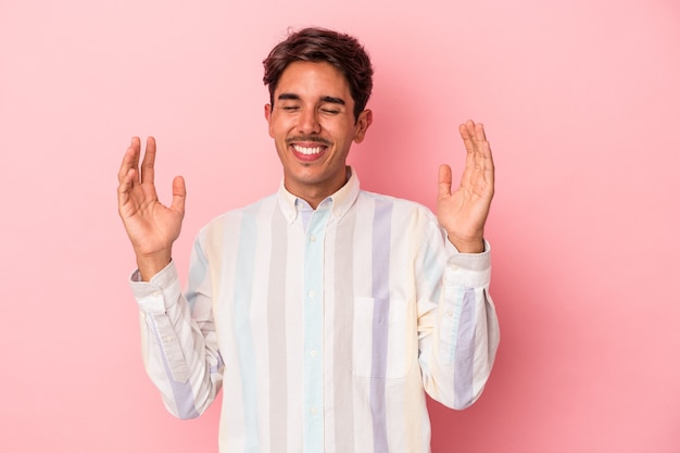 Homem jovem de raça mista isolado no fundo branco alegre rindo muito. Conceito de felicidade.