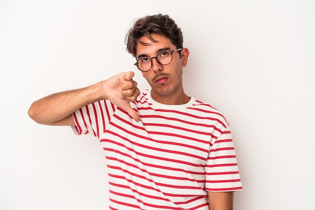 Homem jovem de raça mista isolado no fundo branco, mostrando um gesto de antipatia, polegares para baixo. Conceito de desacordo.