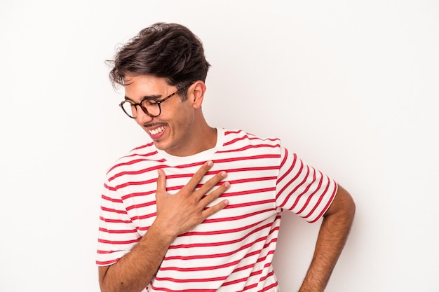 Foto homem jovem de raça mista isolado no fundo branco rindo mantendo as mãos no coração, conceito de felicidade.