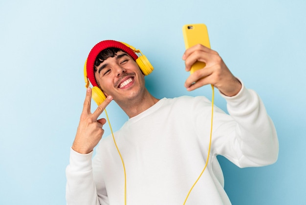 Homem jovem de raça mista, ouvindo música isolada em fundo azul