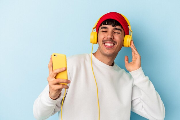 Homem jovem de raça mista, ouvindo música isolada em fundo azul