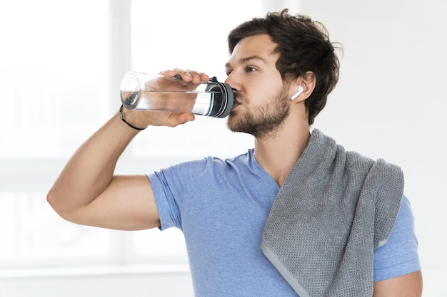 Homem jovem e bonito após treino de fitness no ginásio luminoso