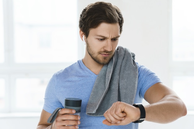 Homem jovem e bonito após treino de fitness no ginásio luminoso