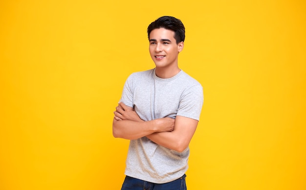 Homem jovem e bonito asiático sorrindo e braços cruzados em amarelo.