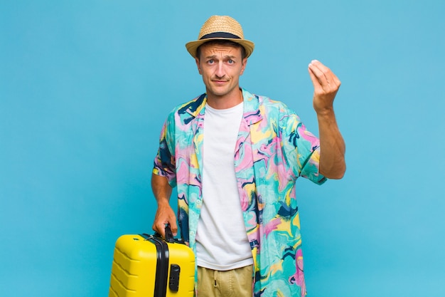 Homem jovem e bonito fazendo capice ou gesto de dinheiro, dizendo para você pagar suas dívidas!