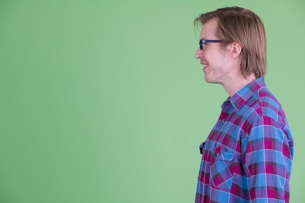 Homem jovem e bonito hippie escandinavo com óculos contra chroma key com fundo verde