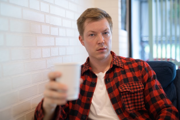 Homem jovem e bonito, moderno, bebendo café na cafeteria