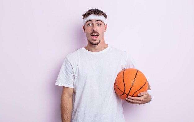 Homem jovem e bonito parecendo muito chocado ou surpreso. conceito de basquete