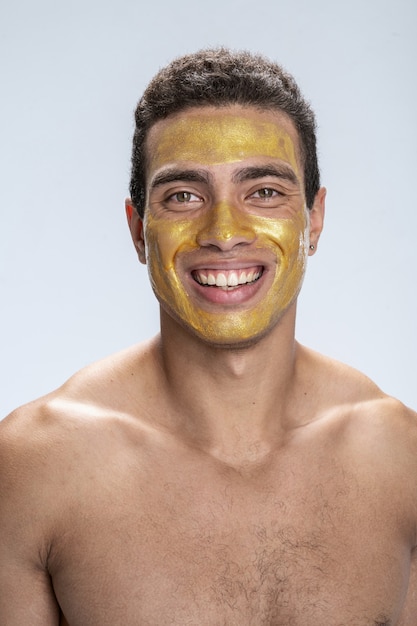 Homem jovem e bonito sorrindo com uma máscara facial