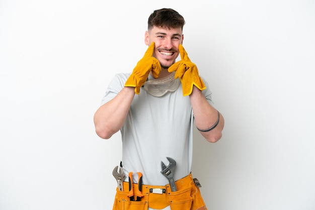 Foto homem jovem eletricista caucasiano isolado no fundo branco sorrindo com uma expressão feliz e agradável