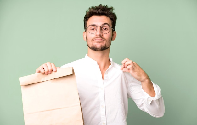 Homem jovem empregado bonito com um saco de papel de comida para viagem