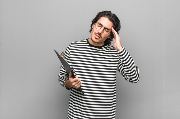 Homem jovem empregado segurando um estoque tocando templos e tendo dor de cabeça.