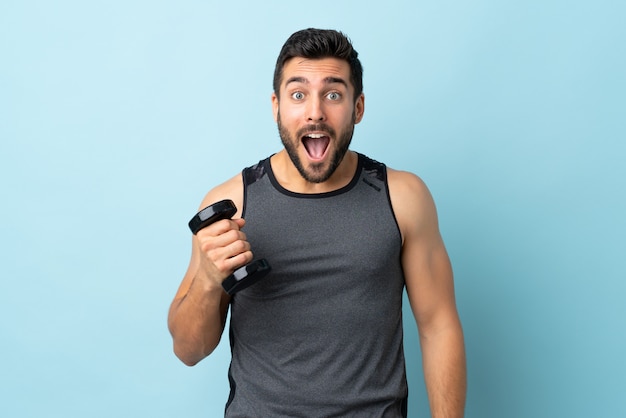 Homem jovem esporte com barba fazendo levantamento de peso com surpresa e expressão facial chocado