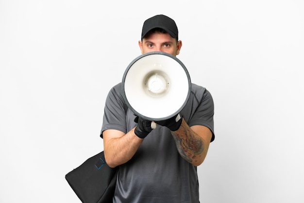 Homem jovem esporte com bolsa esportiva sobre fundo branco isolado gritando através de um megafone