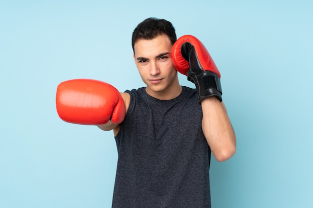 Homem jovem esporte na parede azul com luvas de boxe