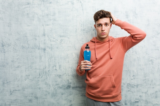 Homem jovem esporte segurando uma bebida energética sendo chocado, ela se lembrou de uma reunião importante.