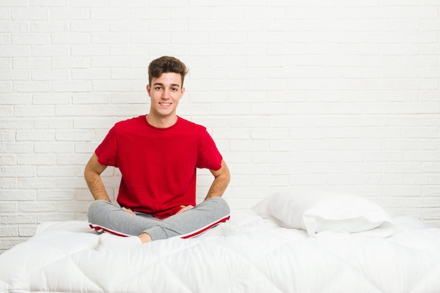 Homem jovem estudante adolescente na cama confiante, mantendo as mãos nos quadris.