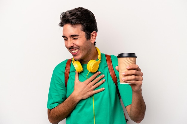 Homem jovem estudante caucasiano bebendo café isolado no fundo branco rindo e se divertindo