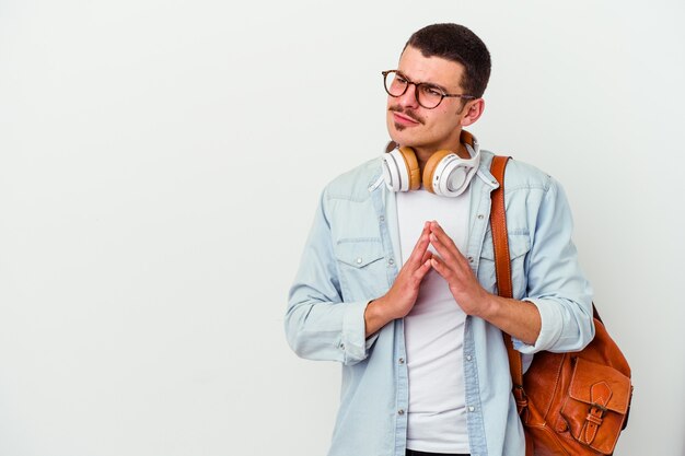 Homem jovem estudante caucasiano ouvindo música isolada no fundo branco, fazendo o plano em mente, estabelecendo uma ideia.