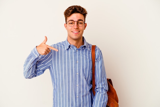 Homem jovem estudante isolado em fundo branco pessoa apontando com a mão para um espaço de cópia de camisa, orgulhoso e confiante