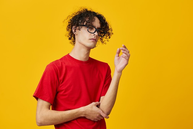 Homem jovem estudante míope pensativo pensativo em óculos engraçados de camiseta vermelha posando isolado sobre fundo amarelo do estúdio A melhor oferta com lugar gratuito para publicidade Conceito de faculdade de educação