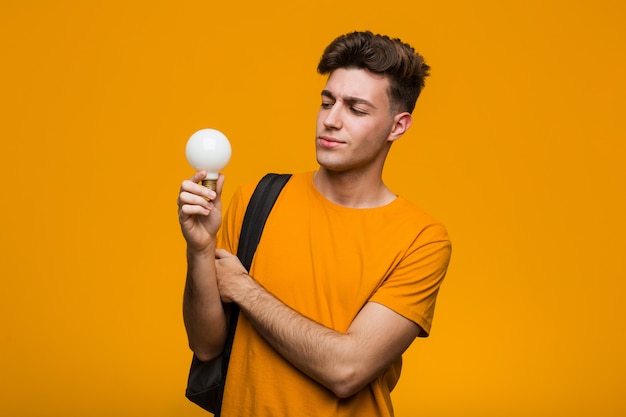 Homem jovem estudante segurando uma lâmpada, roer unhas, nervosas e muito ansiosas.