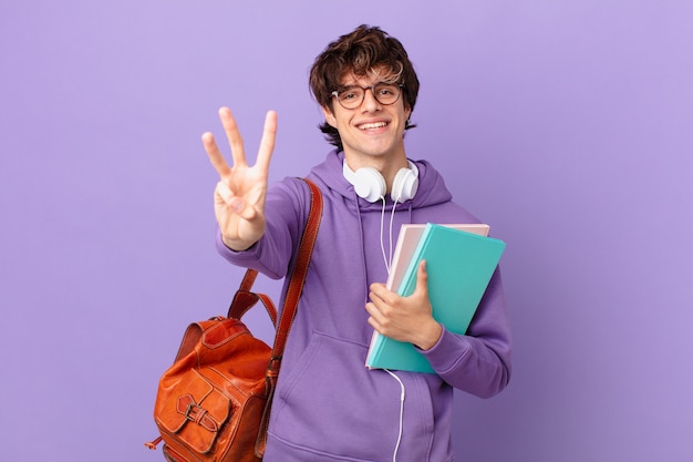 Homem jovem estudante sorrindo e parecendo amigável, mostrando o número três