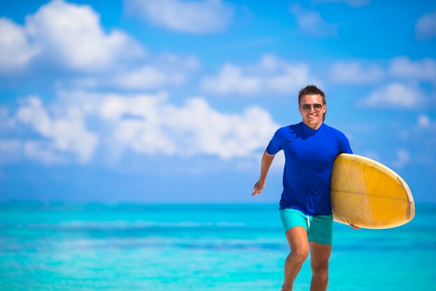 Homem jovem feliz surf runing na praia com uma prancha de surf