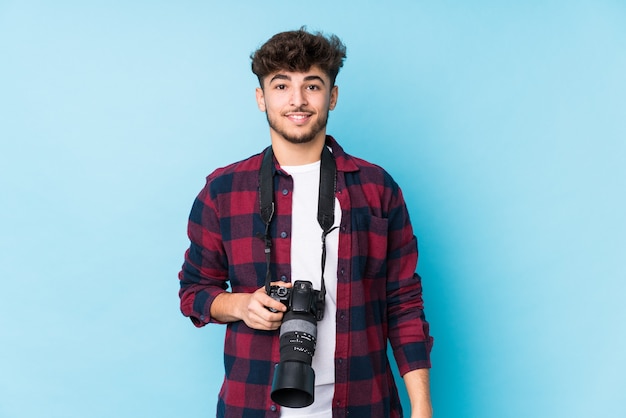 Homem jovem fotógrafo árabe isolado feliz, sorridente e alegre.