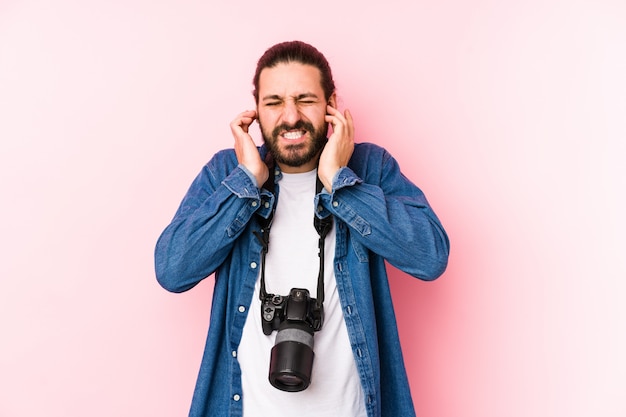 Homem jovem fotógrafo caucasiano cobrindo os ouvidos com as mãos.