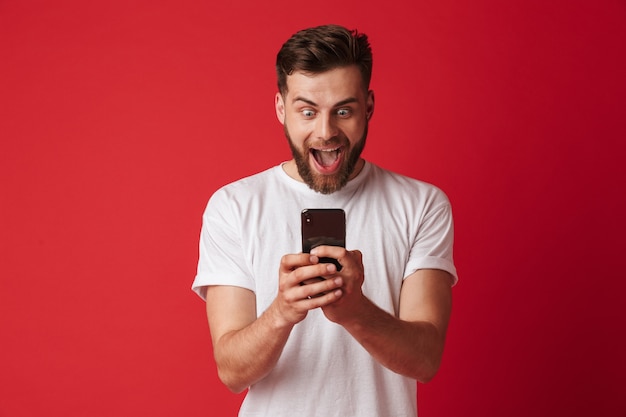 Homem jovem gritando chocado usando telefone celular.