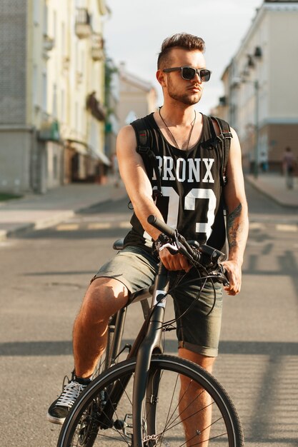 Homem jovem hippie com bicicleta sentado em uma bicicleta