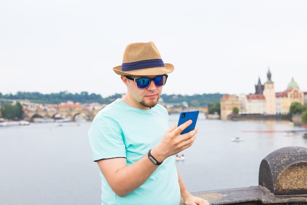 Homem jovem hippie usando telefone celular inteligente ao ar livre