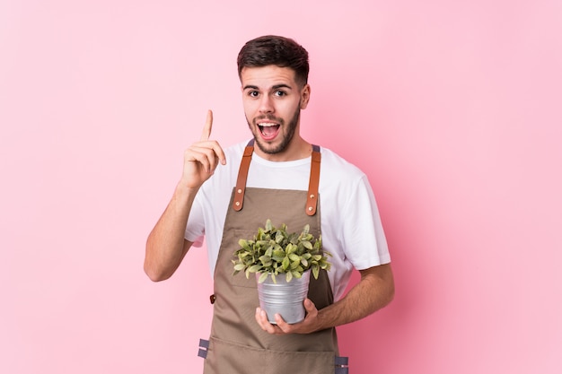 Homem jovem jardineiro caucasiano segurando uma planta, tendo uma ideia