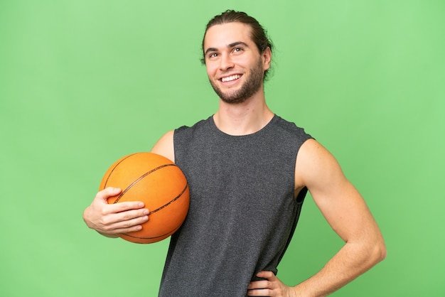 Homem jovem jogador de basquete sobre fundo isolado posando com os braços no quadril e sorrindo