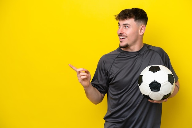 Homem jovem jogador de futebol isolado em fundo amarelo com a intenção de perceber a solução enquanto levanta um dedo