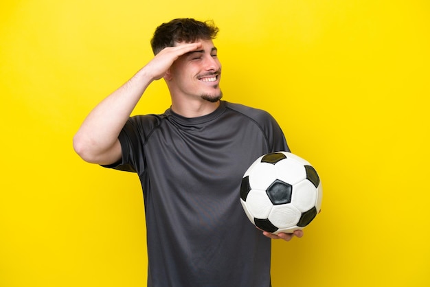 Homem jovem jogador de futebol isolado em fundo amarelo sorrindo muito