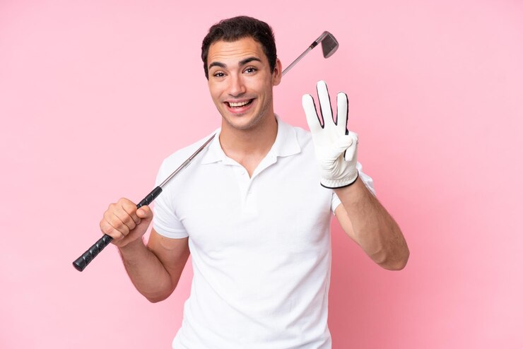 Foto homem jovem jogador de golfe isolado no fundo rosa feliz e contando três com os dedos