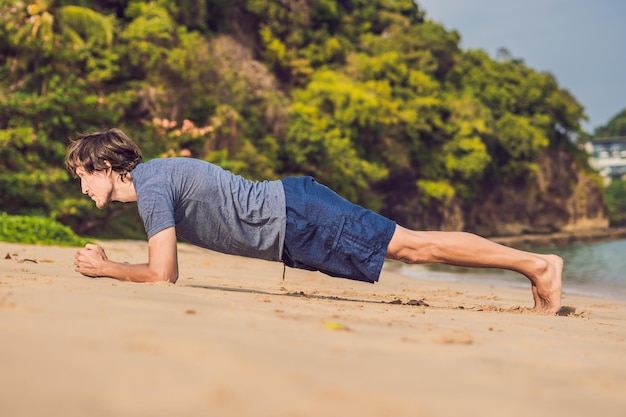 Homem jovem malhando na praia, homem esportivo fazendo exercícios