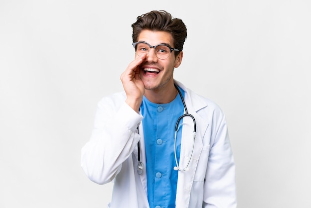 Homem jovem médico sobre fundo branco isolado, gritando com a boca aberta